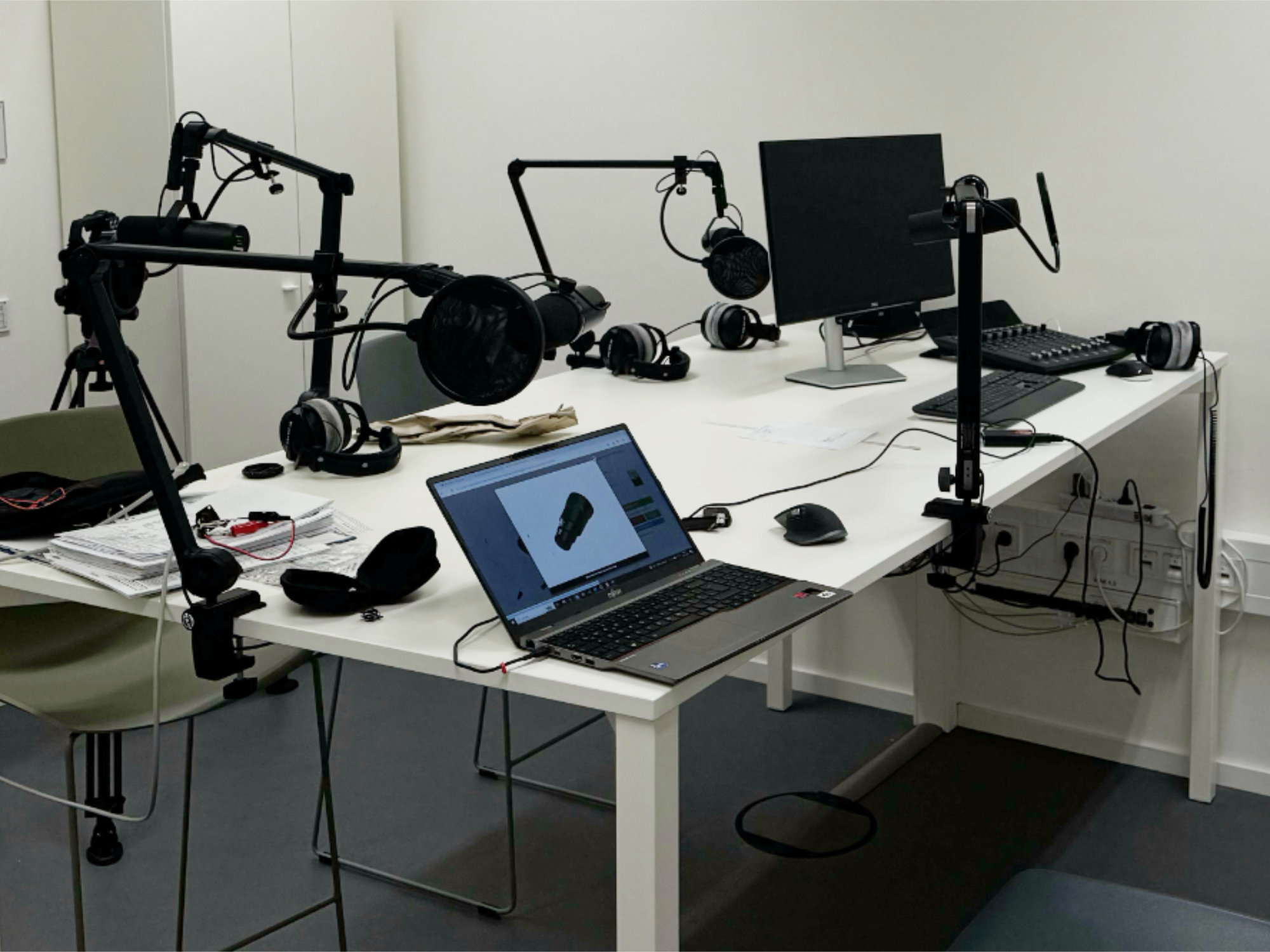 Aufnahmestudio mit Mikrofonen, Kopfhörern und Computern auf einem Tisch.